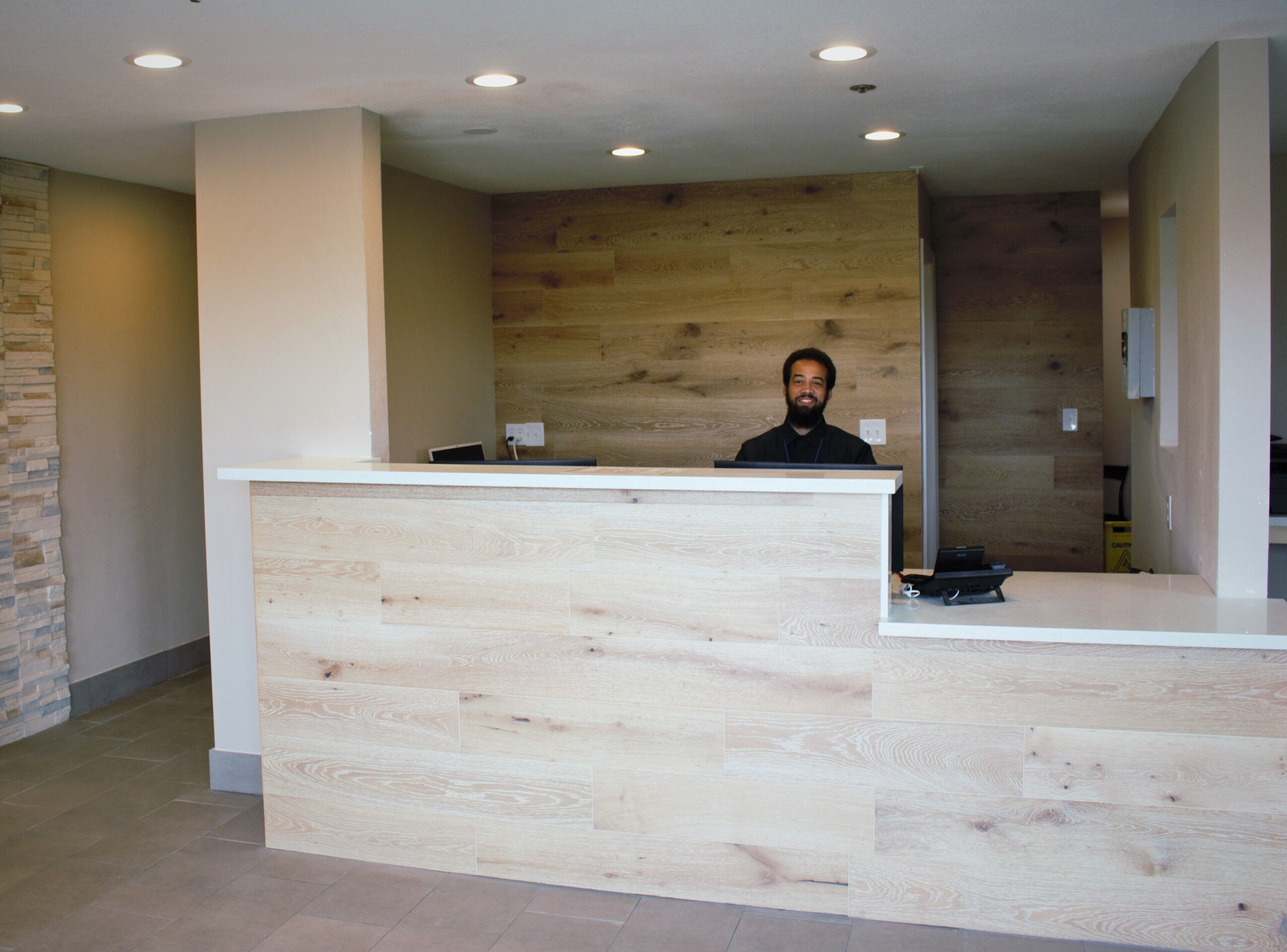 A reception desk with a wooden panel design, a stone accent wall, and recessed ceiling lighting.