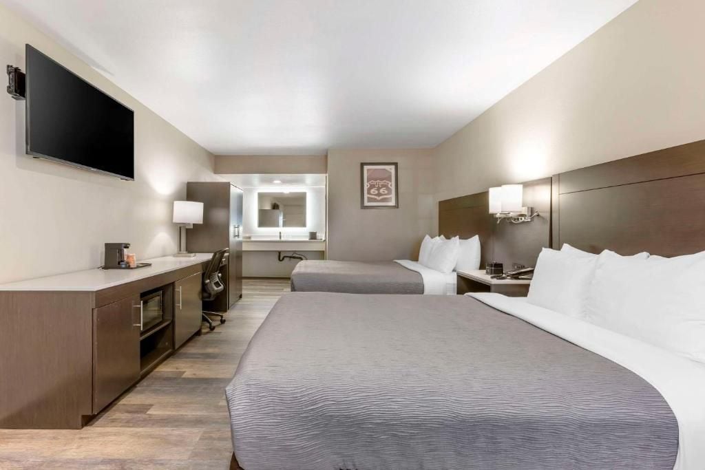 A hotel room with a large bed, a desk, a TV, and a mirror.