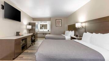 A hotel room with a large bed, a desk, a TV, and a mirror.