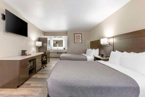 A hotel room with a large bed, a desk, a TV, and a mirror. - Quality Inn Show Low (Show Low)