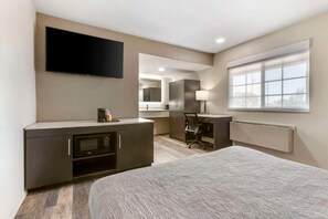 A modern hotel room with a bed, a desk, a flat-screen TV, a microwave, and a window with a view. - Quality Inn Show Low (Show Low)