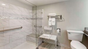 A modern bathroom with a glass-enclosed shower, a white toilet, and a grab bar. - Quality Inn Show Low (Show Low)