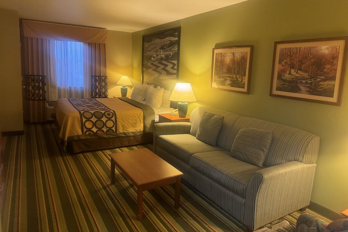 Une chambre d’hôtel avec un lit, un canapé, une petite table et deux lampes.