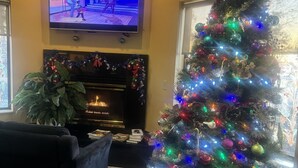 A living room with a Christmas tree, a fireplace, and a television. - Super 8 by Wyndham Sparta (Sparta)