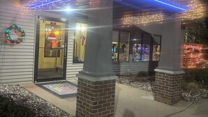 A building with a covered porch adorned with string lights and a Christmas wreath. - Super 8 by Wyndham Sparta (Sparta)