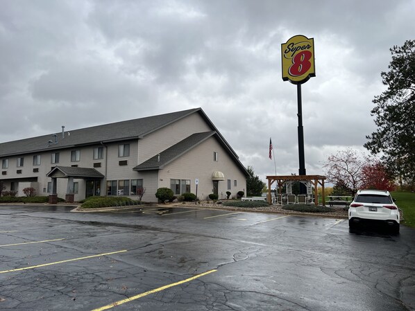 A hotel with a large sign reading "Super 8" and a parking lot with a white car. - Super 8 by Wyndham Sparta (Sparta)