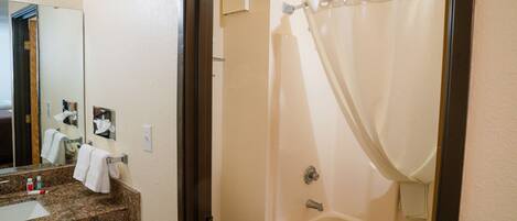 A bathroom with a sink, mirror, toilet, and bathtub.