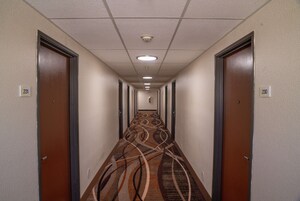 Un pasillo de hotel con alfombra estampada, puertas dobles e iluminación empotrada en el techo.