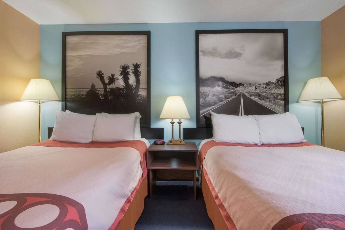 Ein Hotelzimmer mit zwei Betten, einem Nachttisch und zwei Wandlampen.