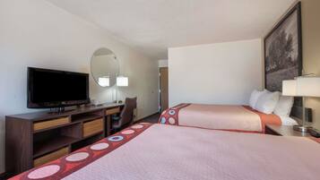 A hotel room with two beds, a desk with a television, a chair, and a mirror.