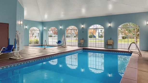 An indoor swimming pool with clear glass windows, blue walls, and a tiled edge. - Garner Hotel Salt Lake City Airport by IHG (Salt Lake City)