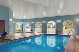 An indoor swimming pool with clear glass windows, blue walls, and a tiled edge.