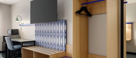 A hotel room with a desk, chair, and a built-in bench with a patterned curtain.