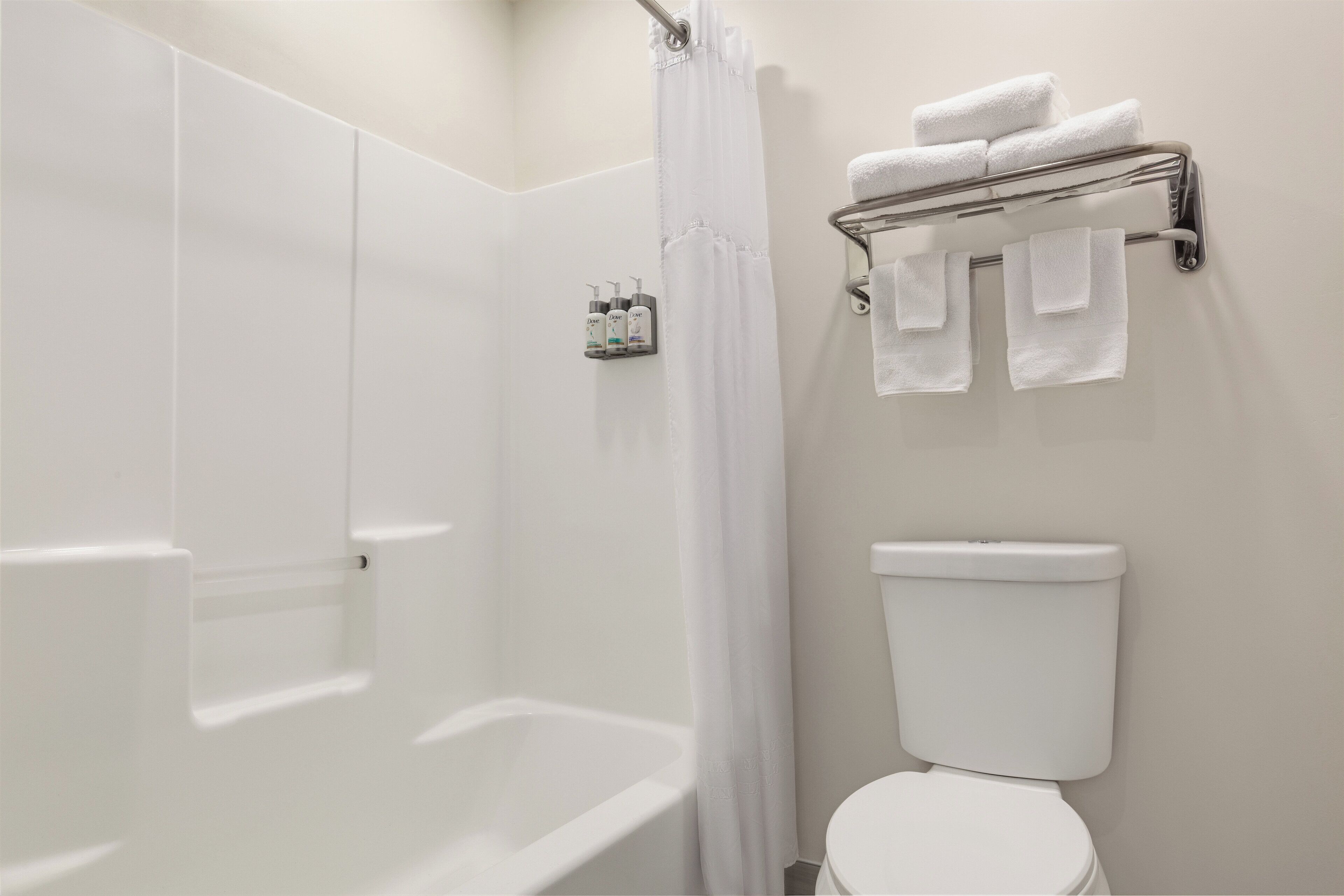 A bathroom with a shower, a toilet, and a towel rack with towels.