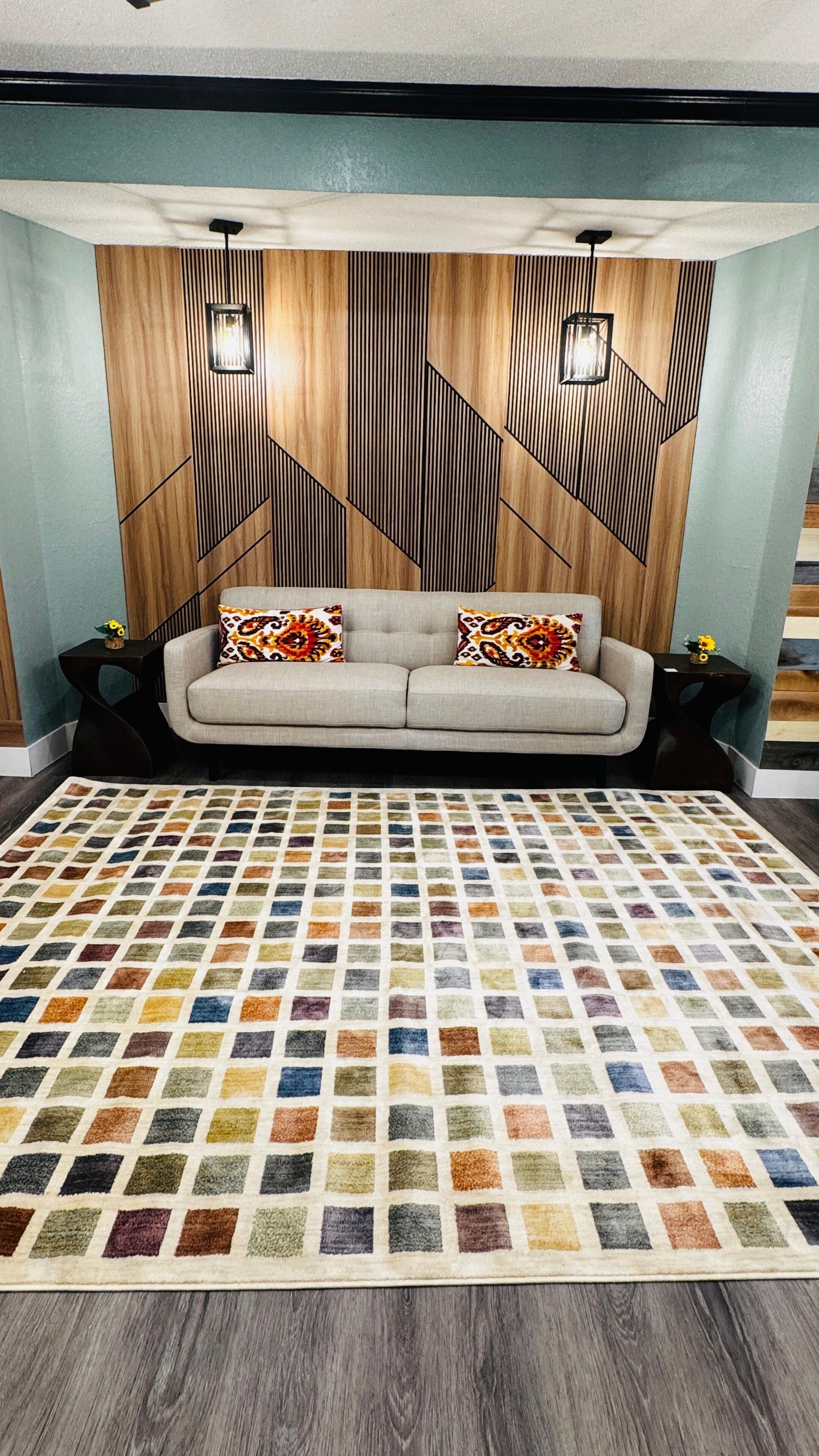 A room with a sofa, patterned rug, and a wall with geometric wooden paneling.