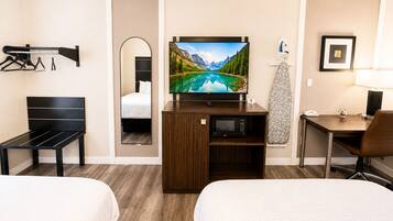 Hotelkamer met twee bedden, een televisie, bureau, stoel, spiegel, kapstok en magnetron.