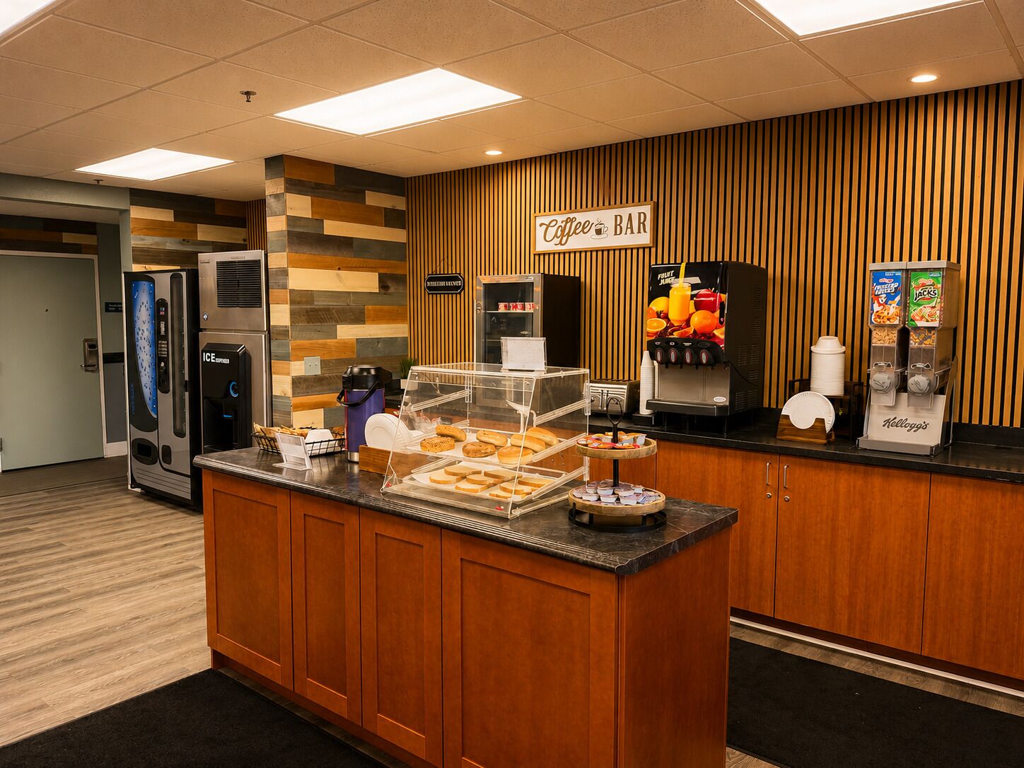 A hotel reception area with a coffee bar, self-service beverage machines, and a pastry display.