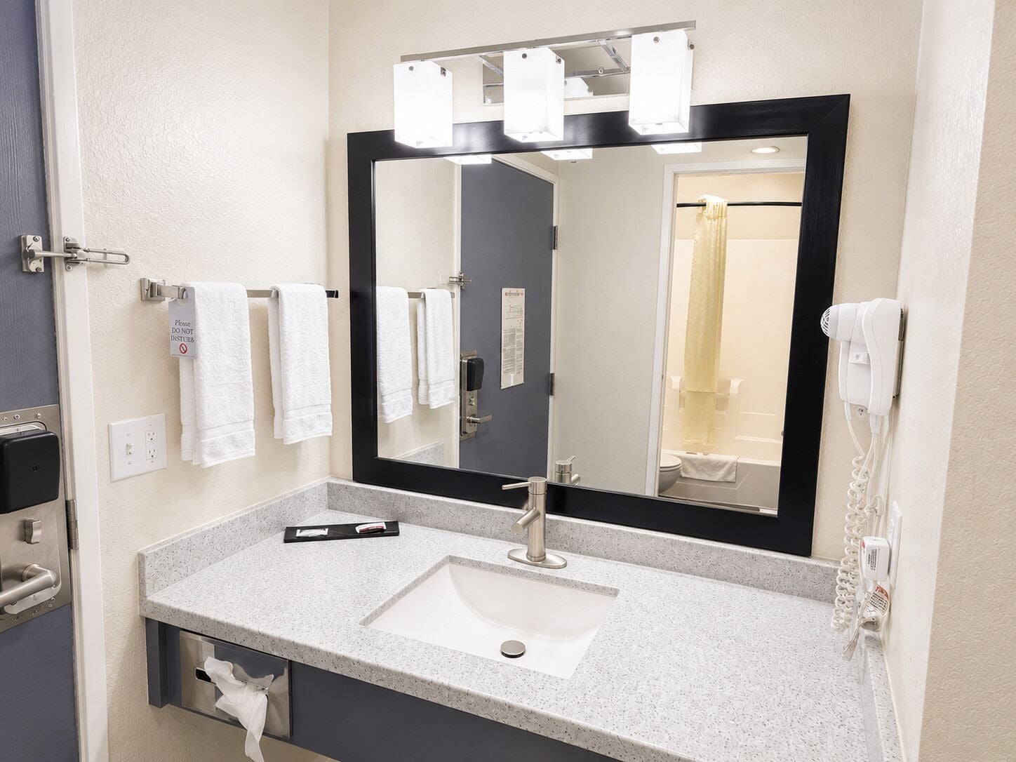 A bathroom with a sink, mirror, towel rack, and a hairdryer.