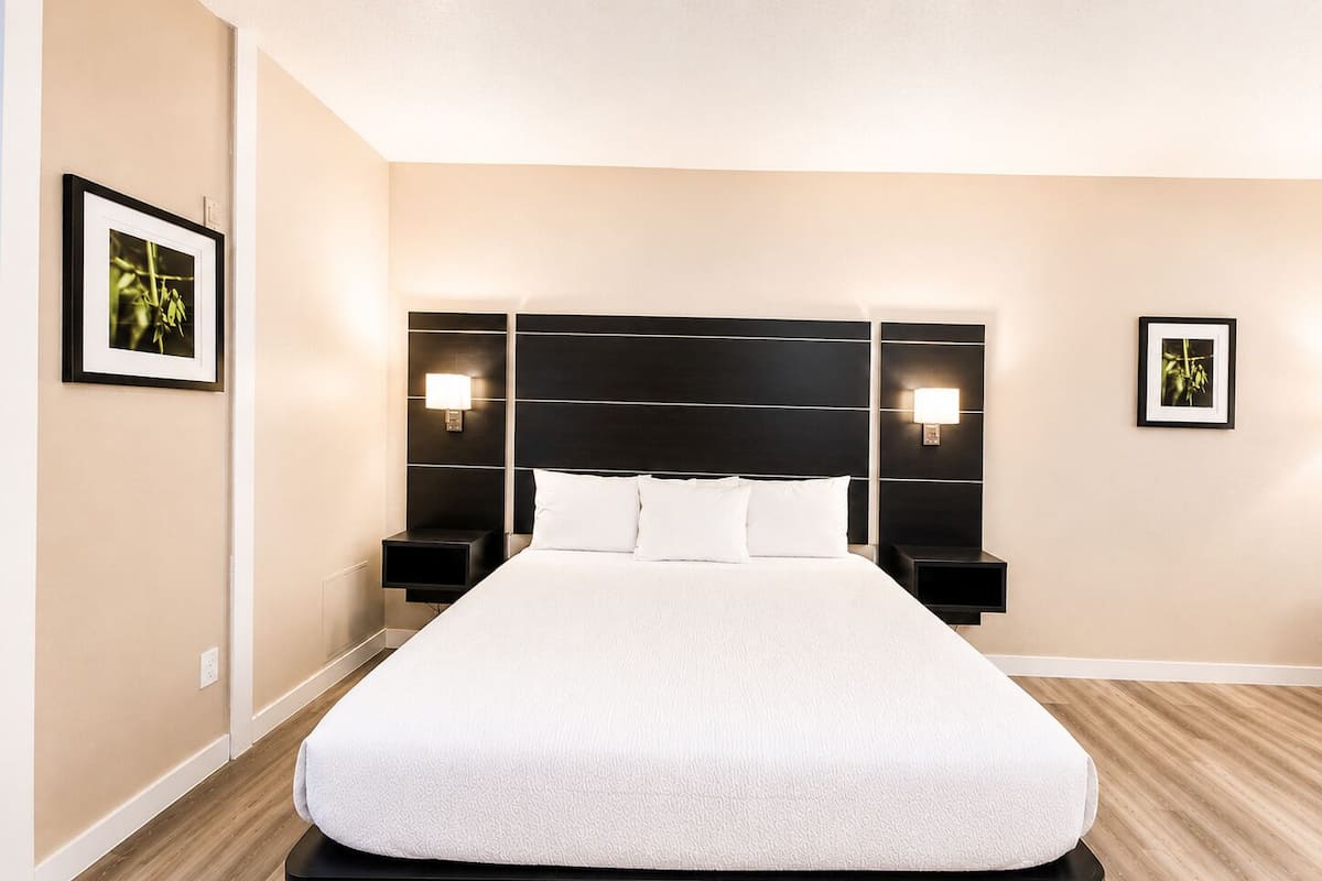 Una habitación de hotel con una cama grande, dos mesitas de noche y lámparas fijadas a la pared.