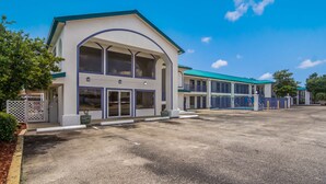 A hotel with a large entrance, multiple windows, and a covered parking area.
