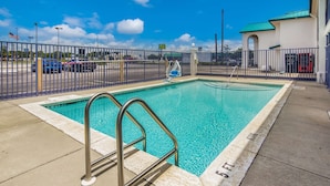 A rectangular swimming pool with a metal ladder, surrounded by a metal fence.
