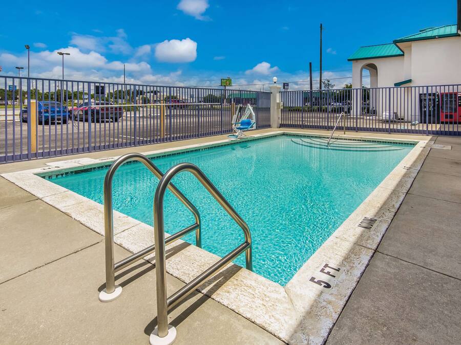 A rectangular swimming pool with a metal ladder, surrounded by a metal fence.
