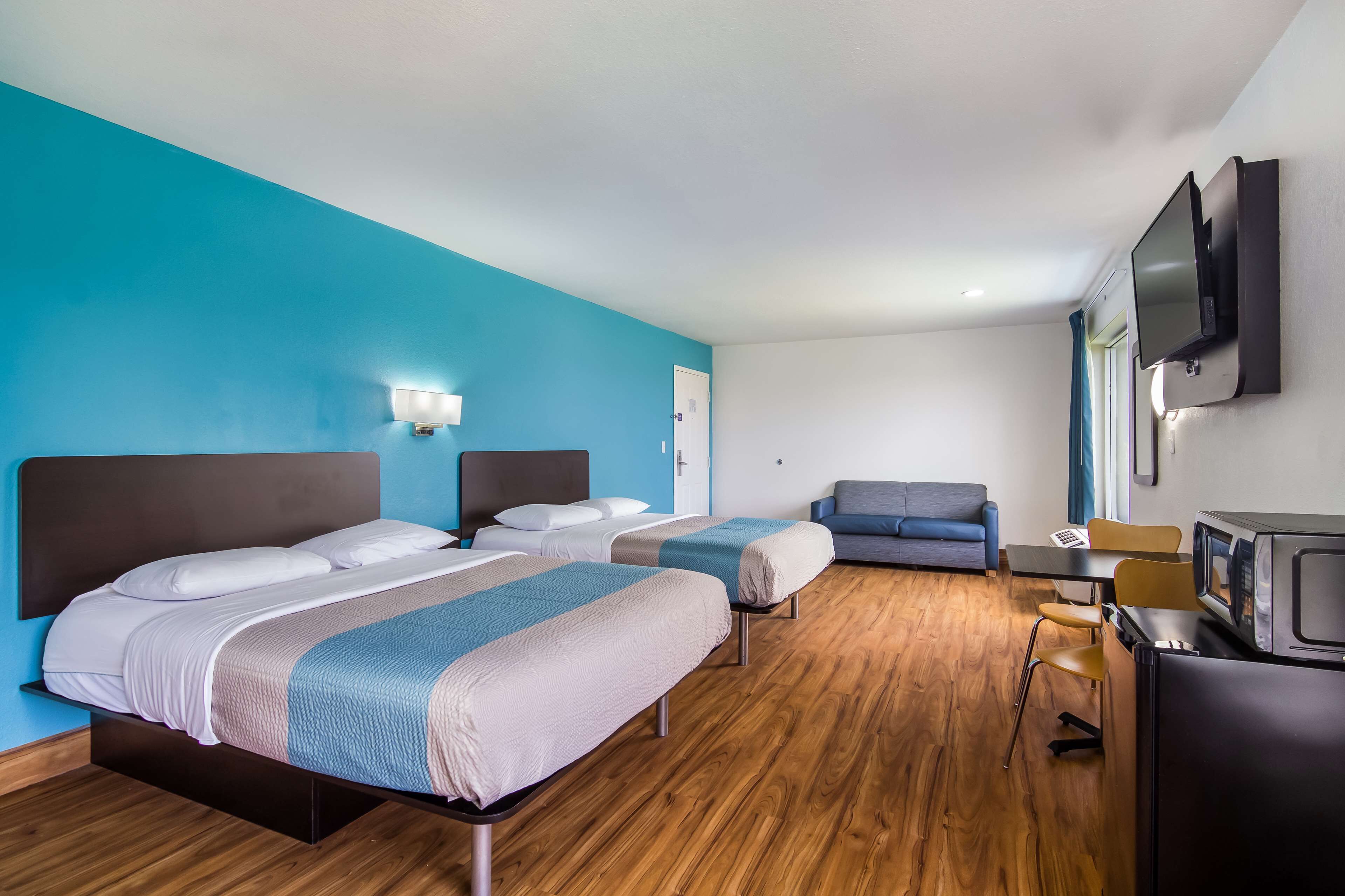 A hotel room with two beds, a desk with a computer, a television, and a microwave.