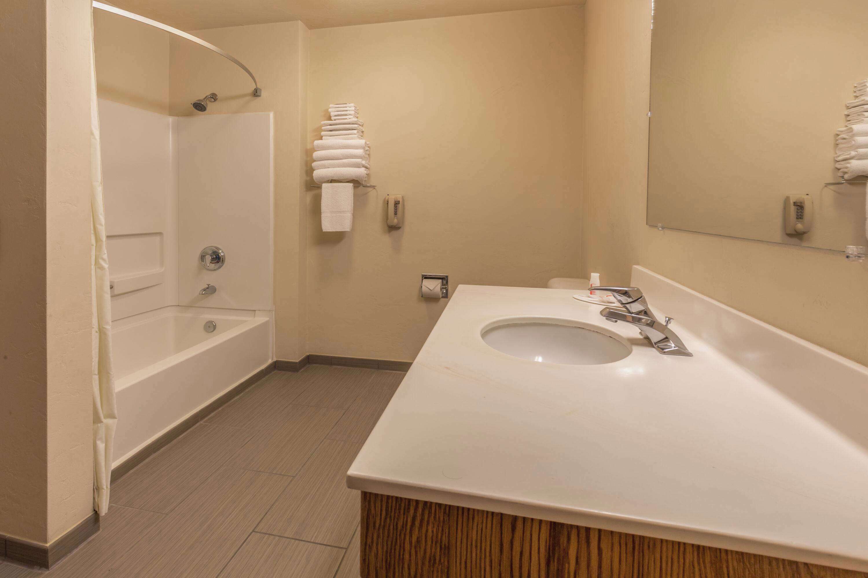 Un baño con bañera, lavamanos, espejo y perchero para toallas.