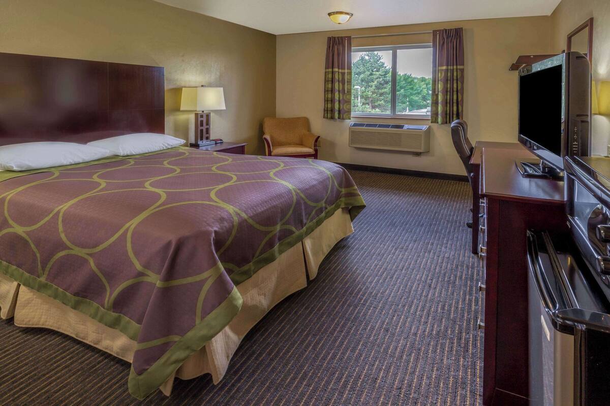Een hotelkamer met een groot bed, een televisie, een bureau en een stoel.