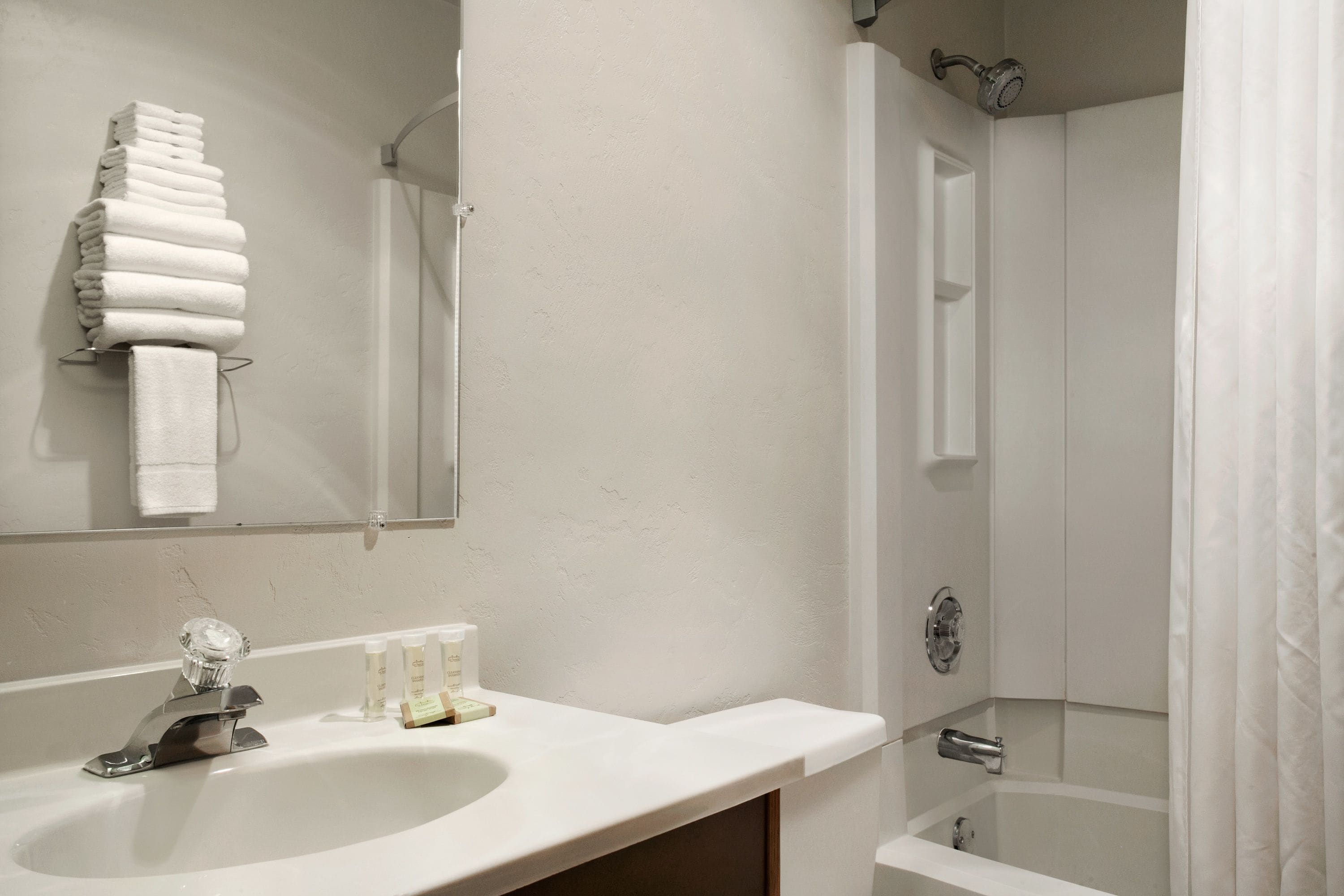 A bathroom with a sink, mirror, and a shower area.