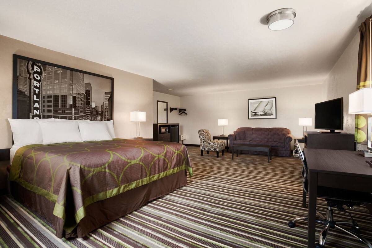 Een hotelkamer met een bed, een slaapbank, een bureau, een televisie en een stadsgezicht op de muur.