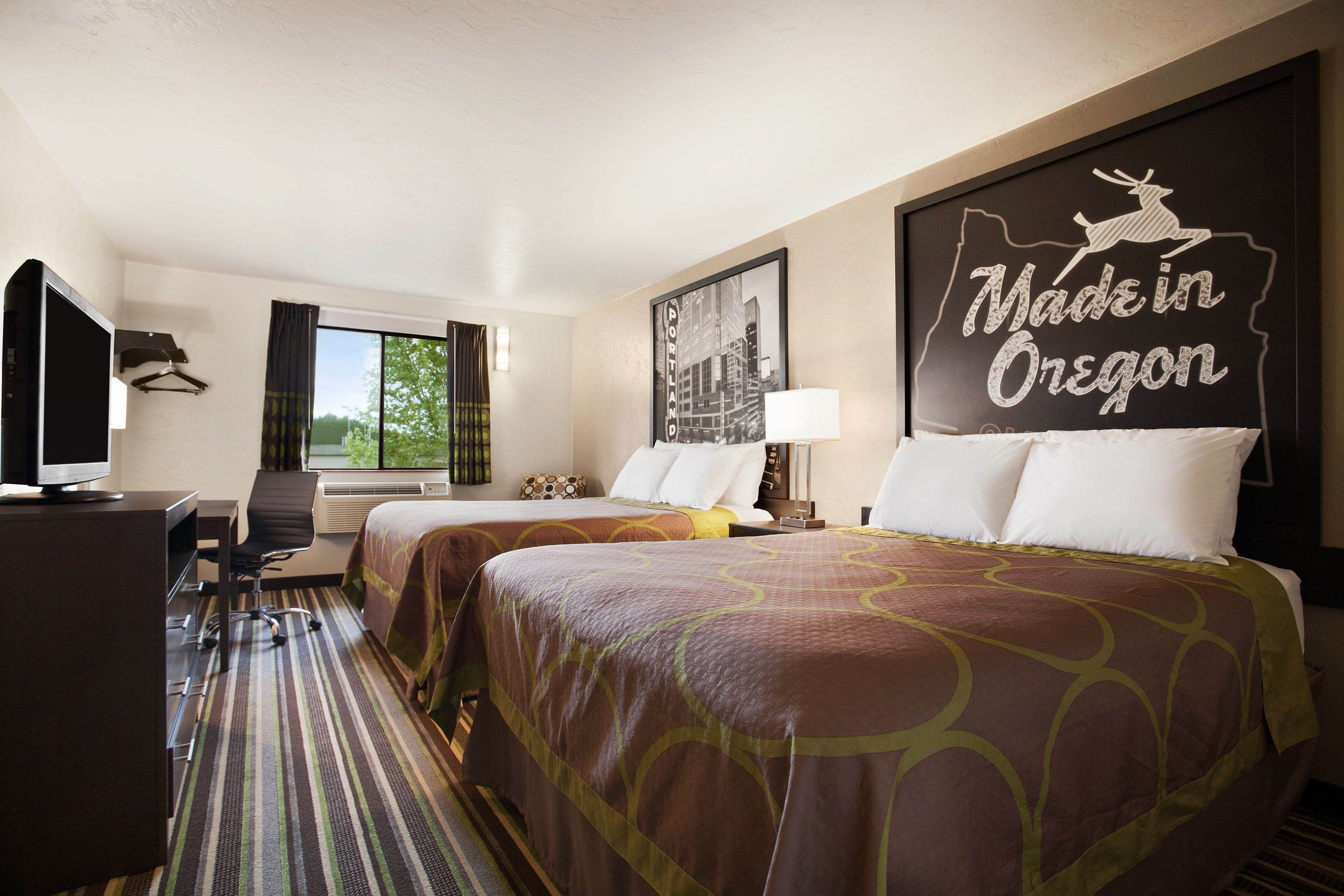 A hotel room with two beds, a desk, a TV, and a window with curtains.