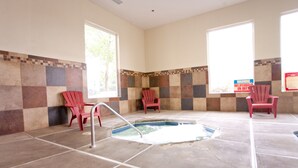 Un área de spa con hidromasaje, paredes de azulejos y sillas rojas.