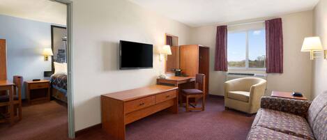 A hotel room with a desk, chair, sofa, and a large window.