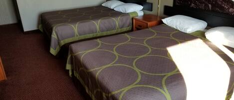 A hotel room with two beds, a nightstand, a lamp, and a painting of a seascape.