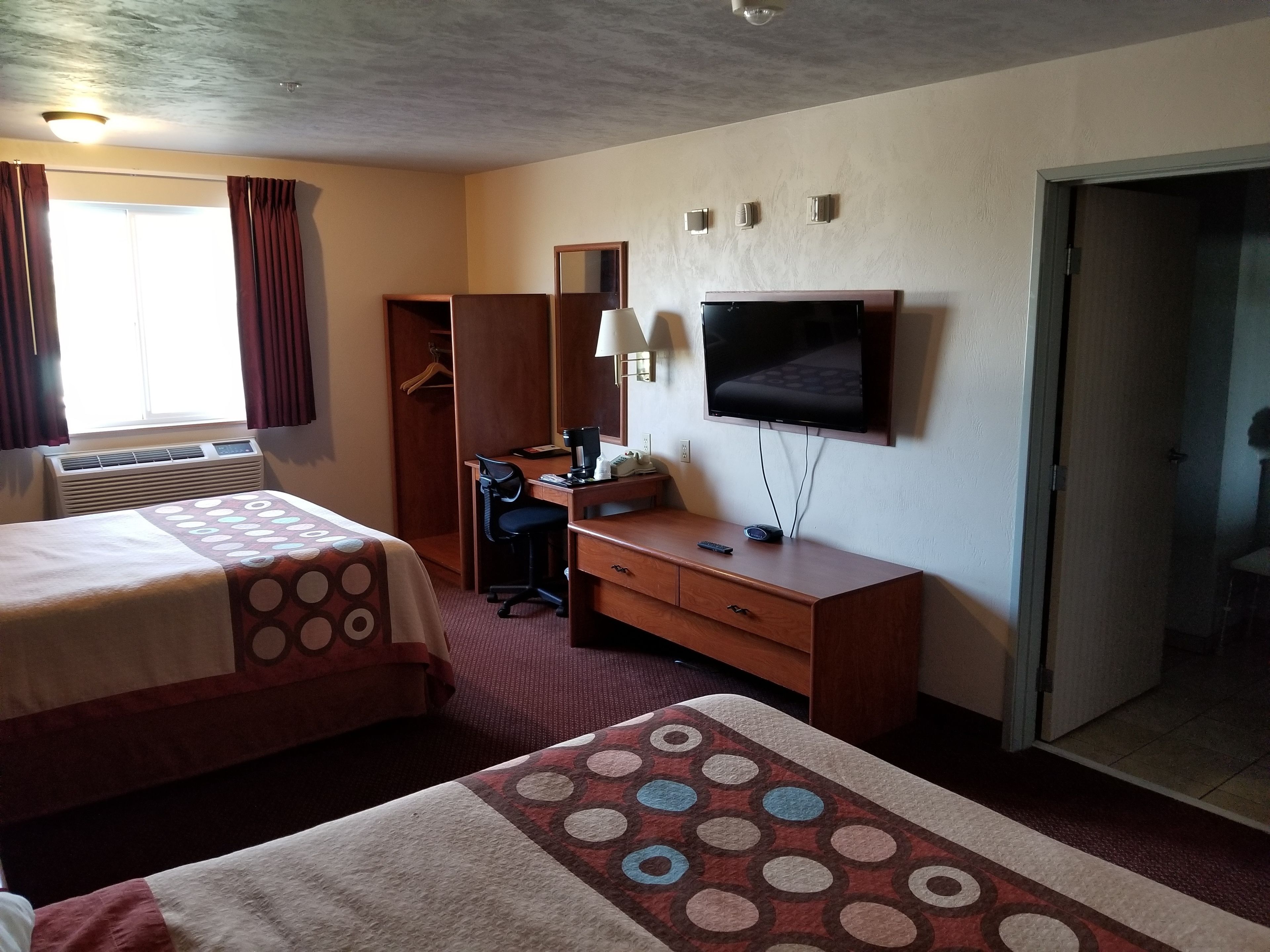A hotel room with two beds, a desk, a television, and a wardrobe.