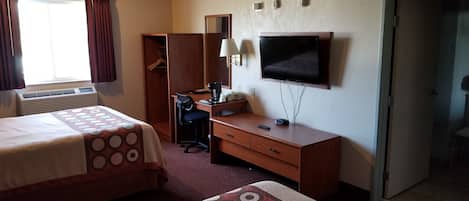 A hotel room with two beds, a desk, a television, and a wardrobe.