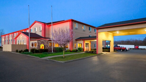 A motel with a red and beige exterior, a parking lot, and a gas station. - Super 8 by Wyndham Bellingham Airport/Ferndale (Ferndale)