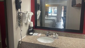 Un baño de hotel con un espejo grande, un lavamanos, un secador de pelo y toallas.