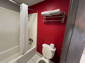 A bathroom with a bathtub, toilet, and a towel rack. - Super 8 by Wyndham Monroe (Monroe)