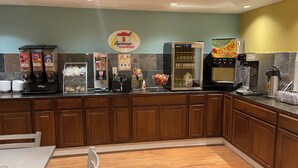 Una barra de desayuno con varios dispensadores de alimentos y bebidas, incluyendo una máquina de café y un refrigerador.
