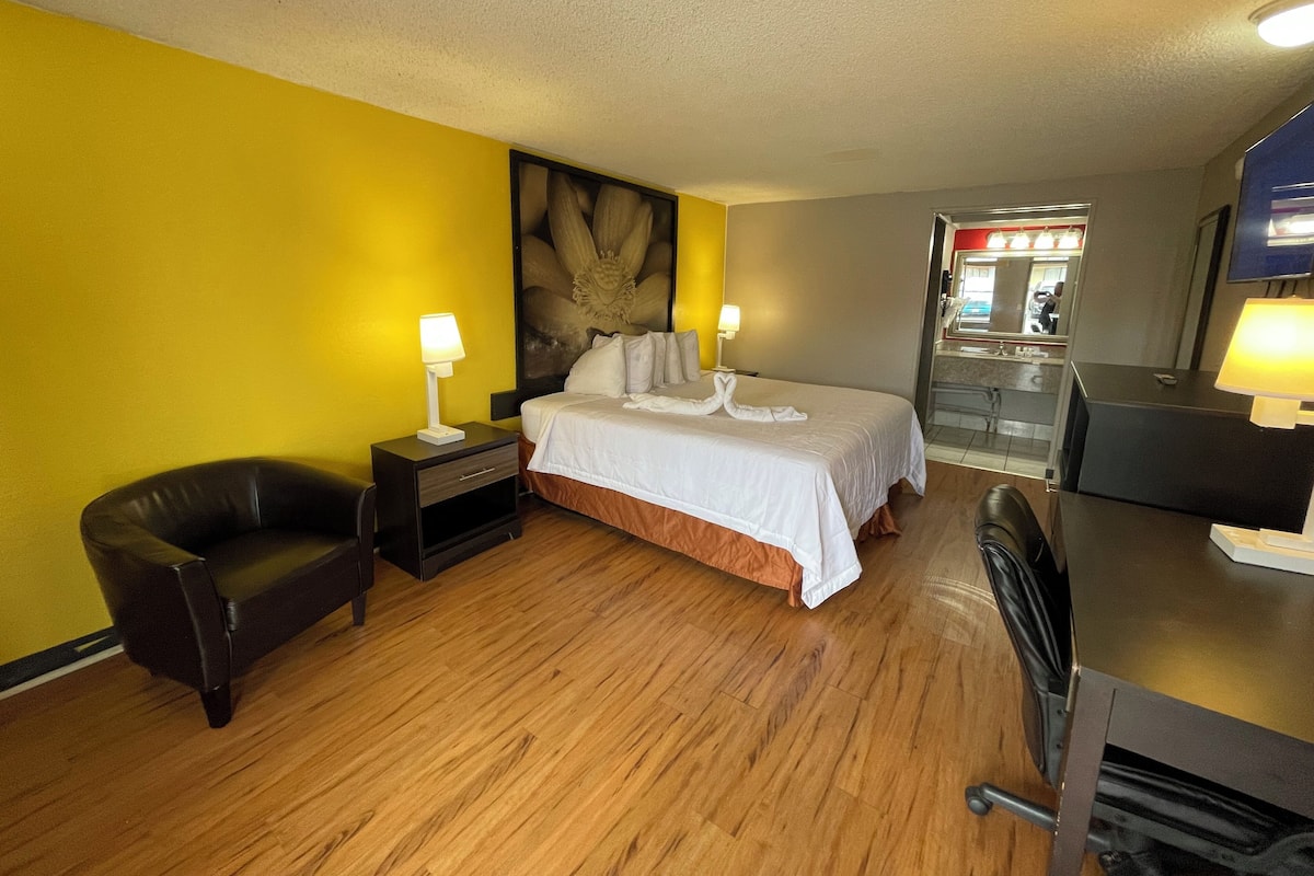 A hotel room with a bed, a chair, a desk, and a minibar.
