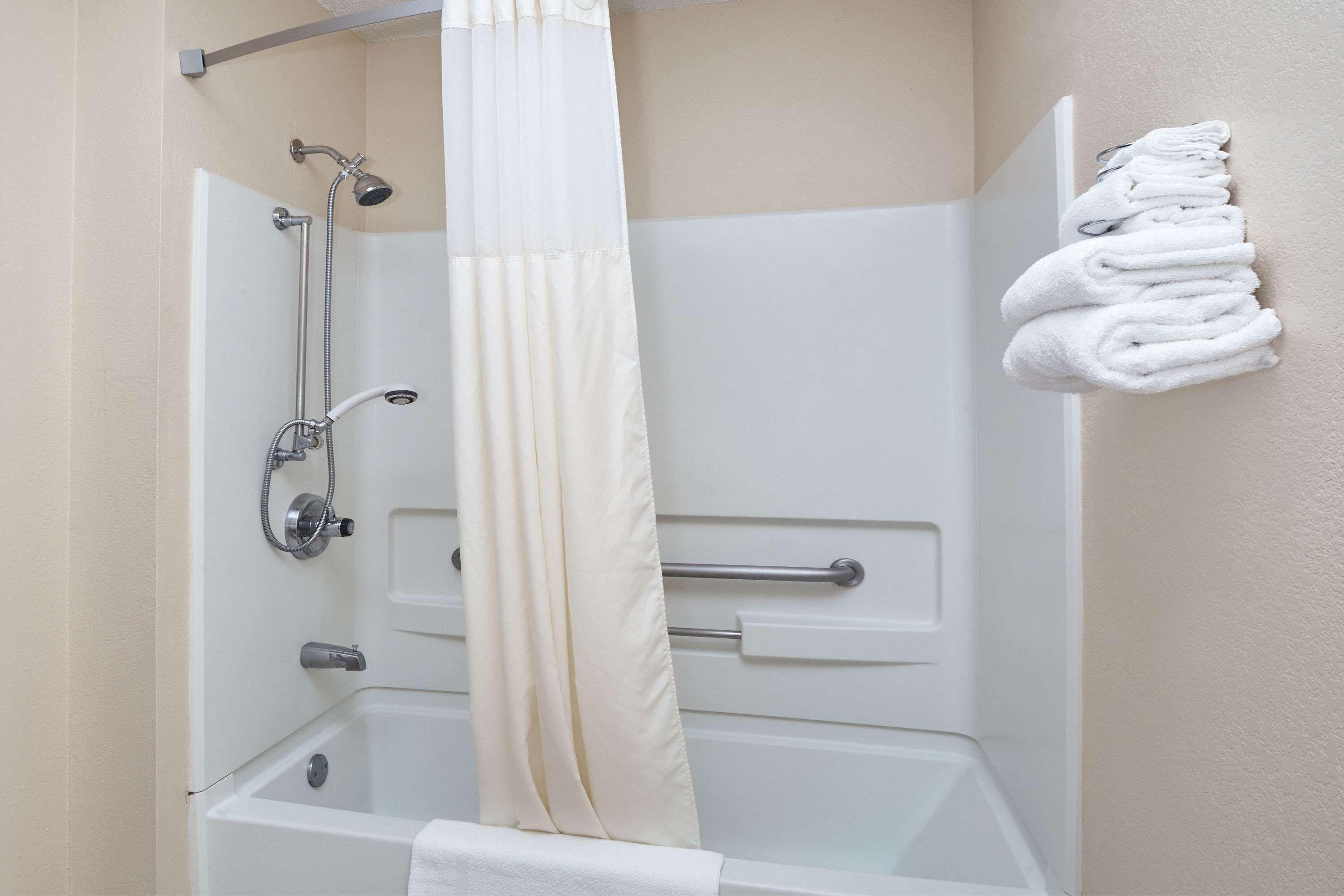 Un baño con bañera, ducha y toallero con toallas dobladas.