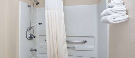 Une salle de bain équipée d’une baignoire, d’une douche et d’un porte-serviettes avec des serviettes pliées.