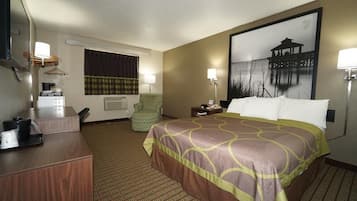 A hotel room with a large bed, a desk, a chair, a lamp, and a painting on the wall.