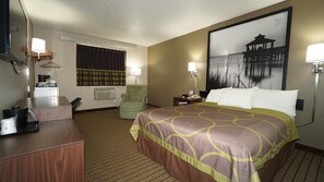 A hotel room with a large bed, a desk, a chair, a lamp, and a painting on the wall. - Super 8 by Wyndham Greenville (Greenville)