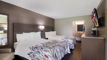 Habitación de hotel con dos camas, un escritorio, un espejo y una televisión.