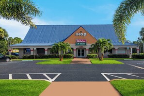 Um Red Roof Inn com telhado azul ladrilhado, uma placa de identificação e um estacionamento.