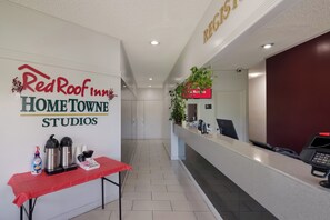 A reception area with a Red Roof Inn sign, a reception desk, a coffee station, and a plant. - Red Roof Inn Vero Beach - I-95 (Vero Beach)