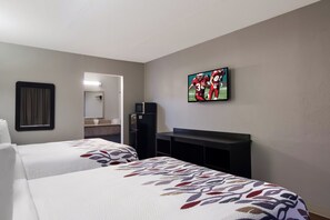 A hotel room with two beds, a flat-screen TV mounted on the wall, a small refrigerator, and a mirror. - Red Roof Inn Vero Beach - I-95 (Vero Beach)